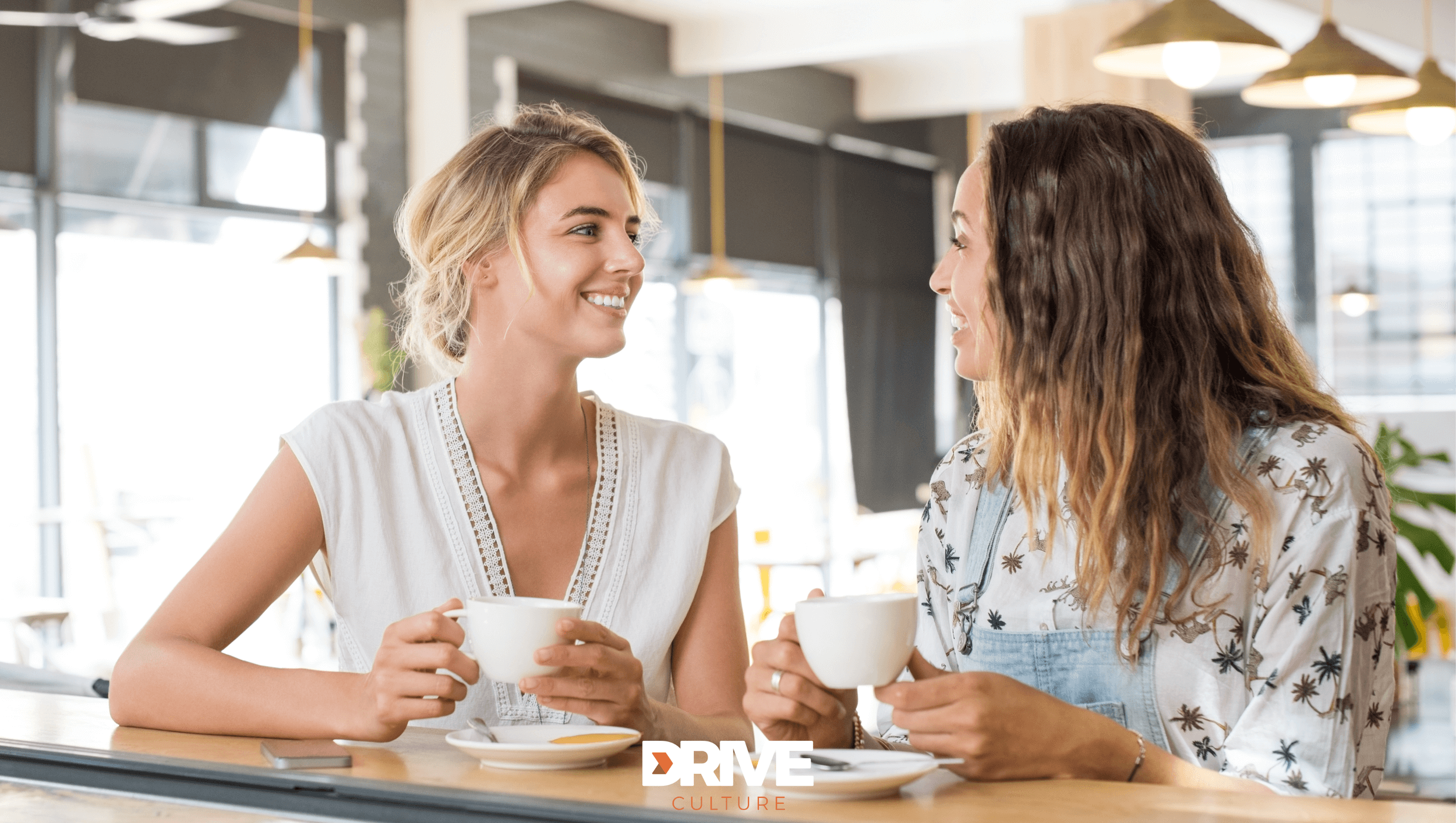 Two women having coffee during a friendly onboarding chat at Drive Culture